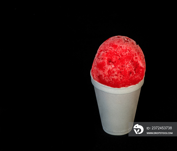 Red Hawaiian shaved ice,  snow cone or shave ice in a white cup on a black background with copy spac