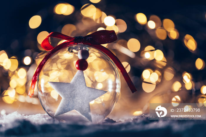 Christmas glass ball with a star inside on snow.