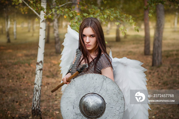 Portrait of a warrior woman in chain mail with steel bracers and wings behind her back. Standing in 