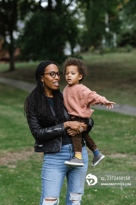 Black mother holding biracial son at park