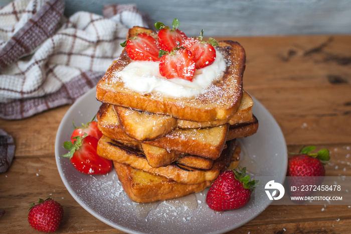 French toast with fresh strawberries, coconut shreds and honey, on wooden background