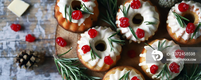 Christmas muffins with rosemary, white icing and red berries. Elegant holiday cakes. Christmas compo