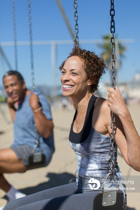 Happy senior woman on swing set on sunny beach