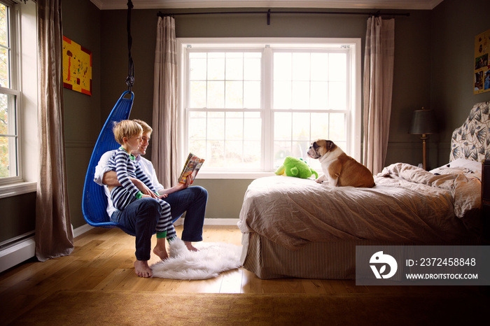 Boy reading book with father at home