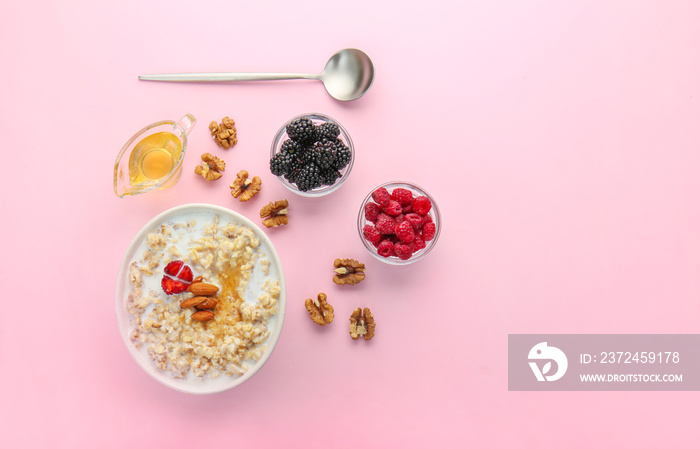 Tasty sweet oatmeal in bowl with nut, berries and honey on color background