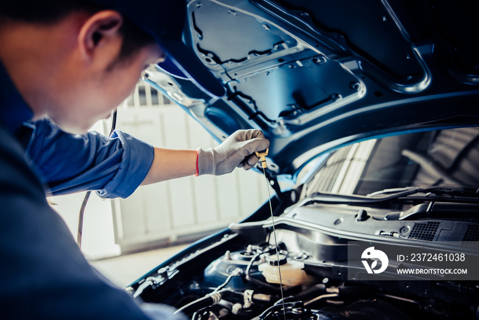 汽车修理中，汽车修理工手持检查齿轮油，按客户索赔单对车辆进行维修