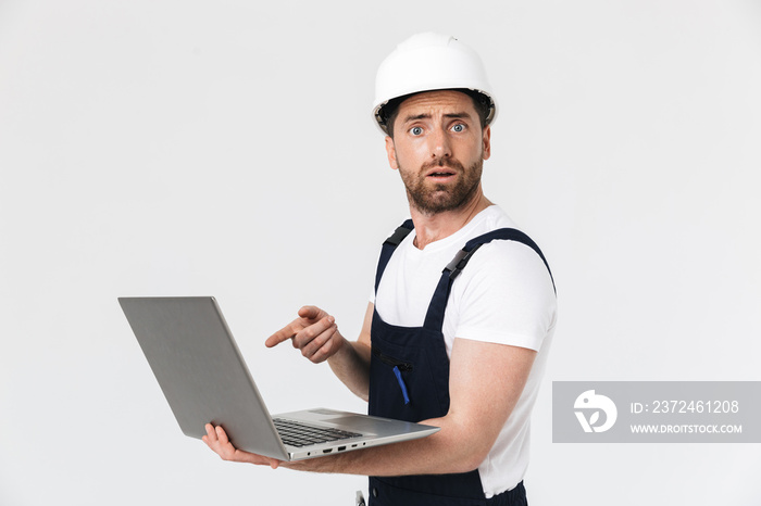 Confident bearded builder man wearing overalls standing