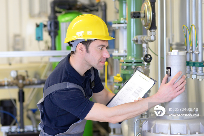 Fitter checks a technical plant in an industrial plant  // Monteur kontrolliert eine technische Anla