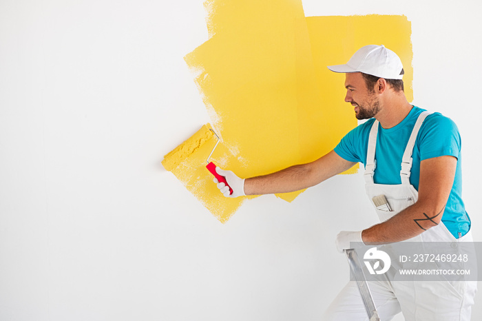 Worker painting wall in yellow color