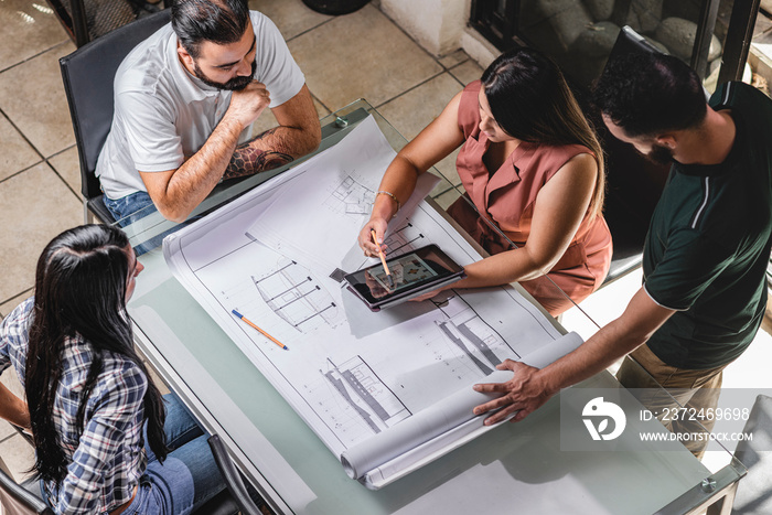 Vista superior de un Grupo de profesionales analizando planos constructivos e imágenes de un proyect