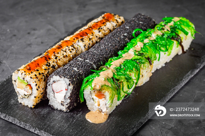 appetizing set of sushi roll on a black stone plate