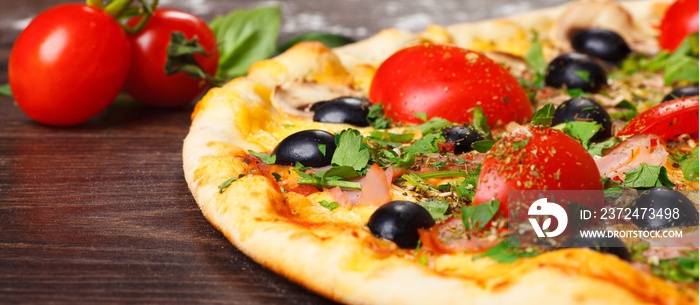 意大利披萨配融化的奶酪、红樱桃番茄、黑橄榄、火腿和绿叶