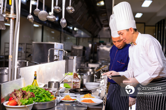 The male executive chef discussing the menu with his colleague in the kitchen.