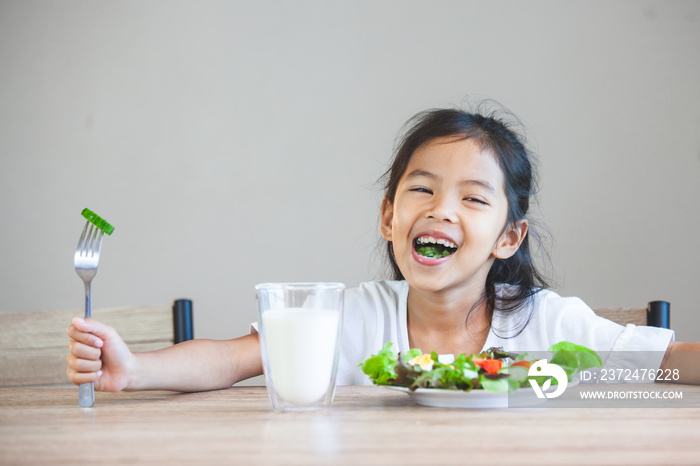 Cute asian child girl eating healthy vegetables and milk for her meal