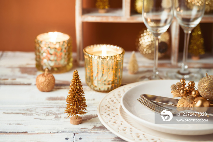 Festive table setting for Christmas holiday celebration with plate, candle and decorations.