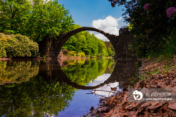 Spiegelung der Rakotzbrücke rund Kreis in Kromlau Park mit Bäumen und Teich Wasser