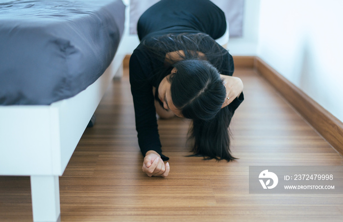 亚洲女子弯腰在床下寻找丢失的东西