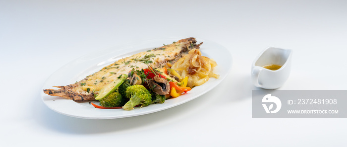 Sole meunière fish with grilled vegetables and caramelized onions on a white plate with white backgr