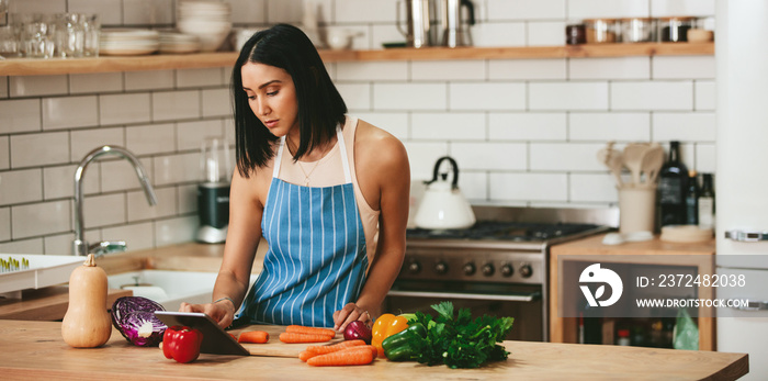 Beautiful woman watching recipe to prepare food in kitchen