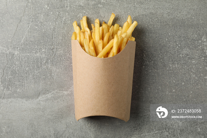 Slices of hot french fries in box on grey background, space for text. Top view