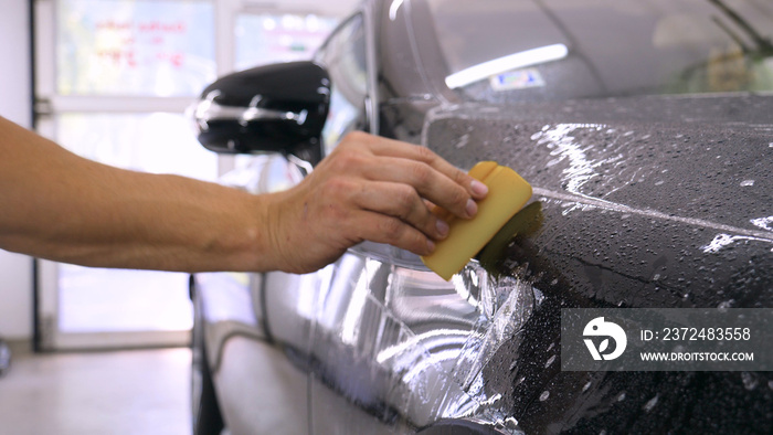 Close up to PPF installation process on a front headlight and hood. PPF is a Paint Protection Film w