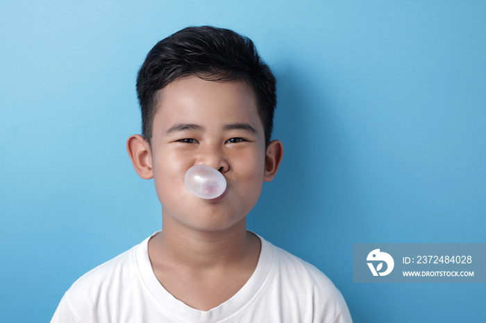 Cute Asian boy eating bubble gum and blow balloon