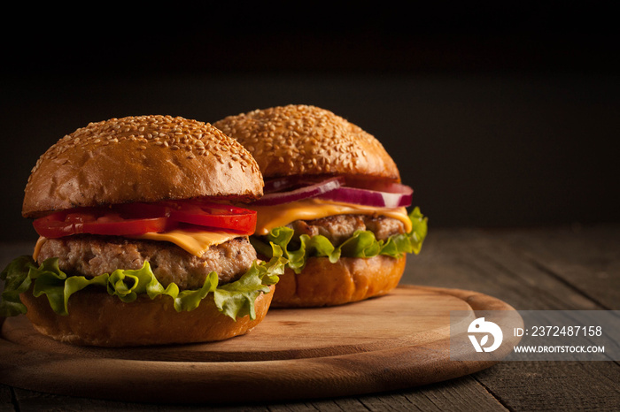 Home made hamburger with beef, onion, tomato, lettuce and cheese. Fresh burger close up on wooden ru