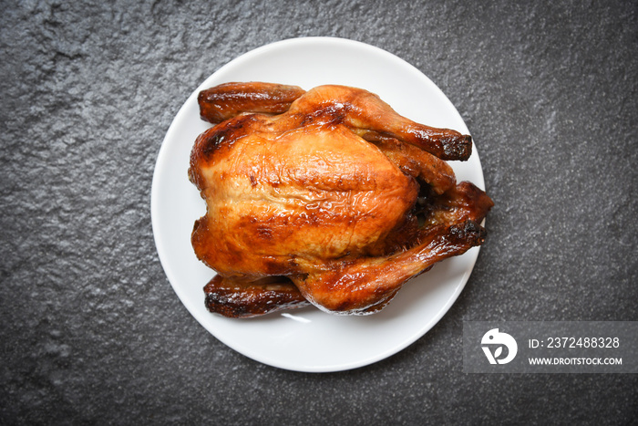 烤鸡/烤整只鸡在白色盘子上烤，俯视图为深色背景