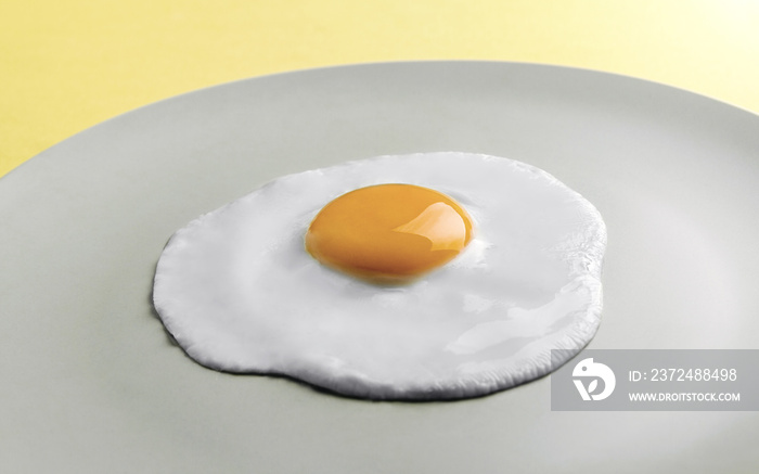 Fried egg on round plate on yellow background