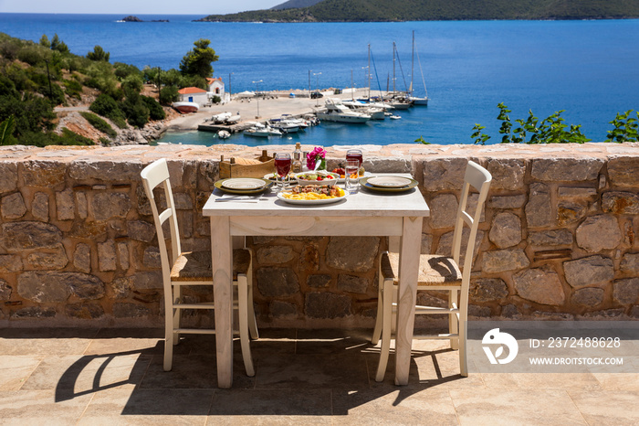 一张两人桌，桌上有鸡肉苏夫拉基和薯条、希腊沙拉、小吃和饮料