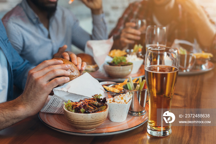 Friends eating burgers and enjoying beer in bar