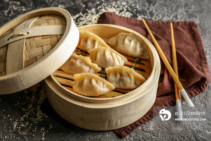 Bamboo steamer with tasty Japanese gyoza on grunge background