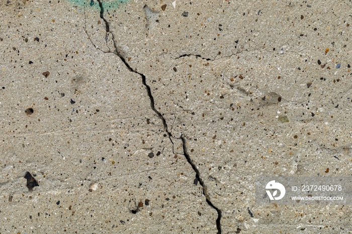 Rough textured surface of cracked concrete foundation slab.