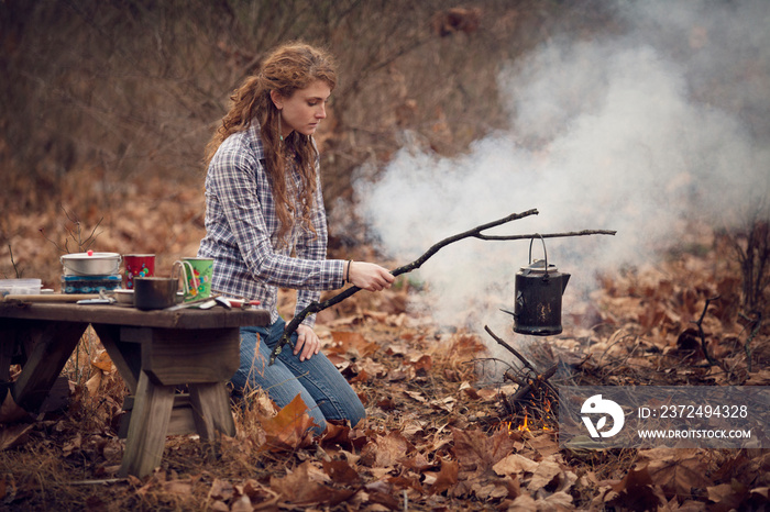 Young woman cooking in forest