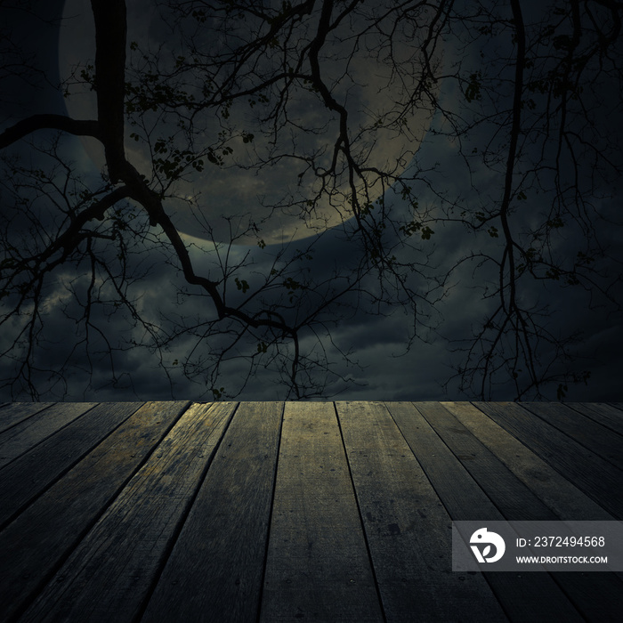 Old wooden table over dead tree, moon and spooky cloudy sky, Halloween background