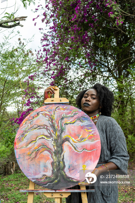 artist standing proudly beside her painting