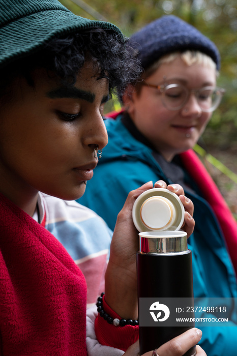 Women drinking from insulated drink container while camping