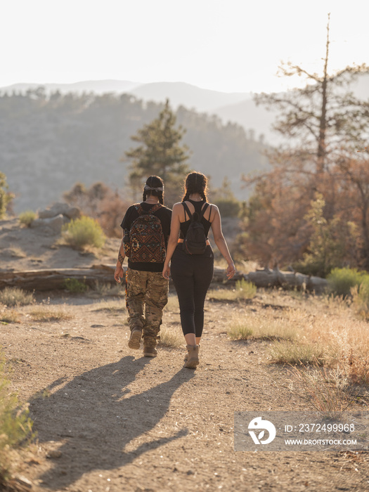 Vertical image of two young Indigenous friends hiking down a mountain