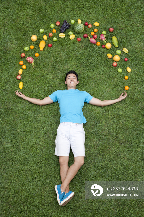 年轻男子和水果在草地上