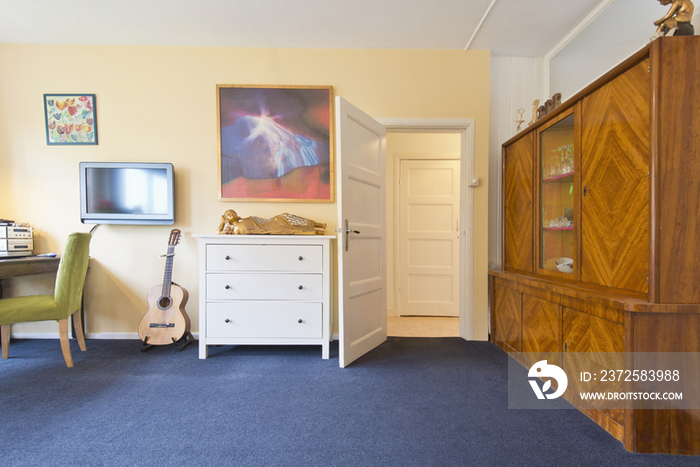 Wall to wall carpet in tidy living room with study desk by the window at home