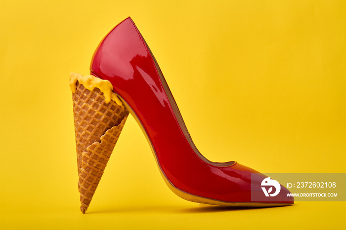 Ice cream cones used as a high heel. Original footwear design concept. Isolated on yellow backgroun