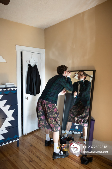 non-binary caucasian person with short hair getting dressed in mirror