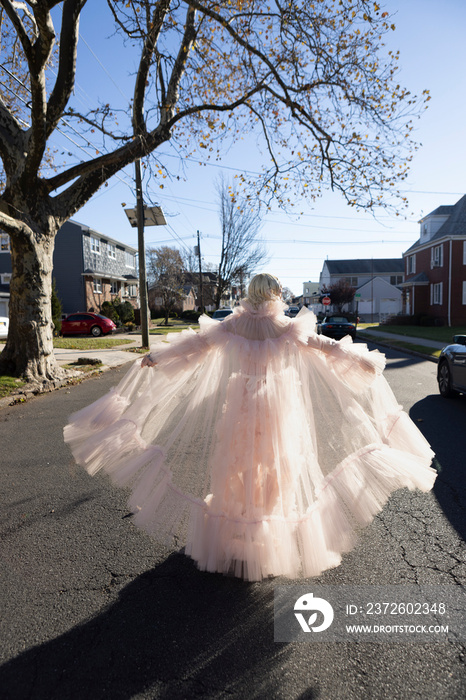 fashion portrait of non-binary person wearing pink tulle dress in suburbia