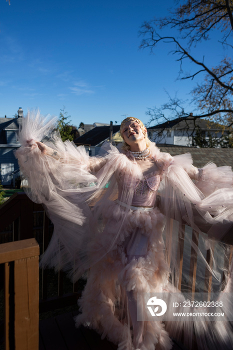 fashion portrait of non-binary person wearing pink tulle dress in dramatic light