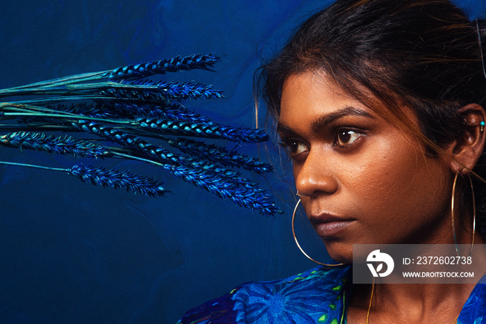 来自马来西亚的深色皮肤印度妇女的肖像，背景为深蓝色，蓝色花朵
