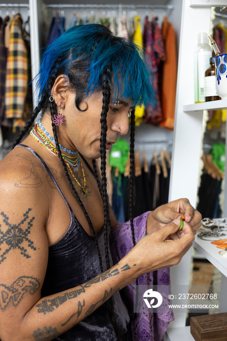 indigenous non-binary artist with blue hair getting dressed