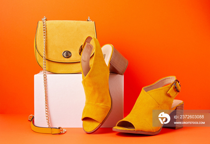 Yellow female fashion accessories, shoes and handbag over orange background. Beauty, shopping, urban