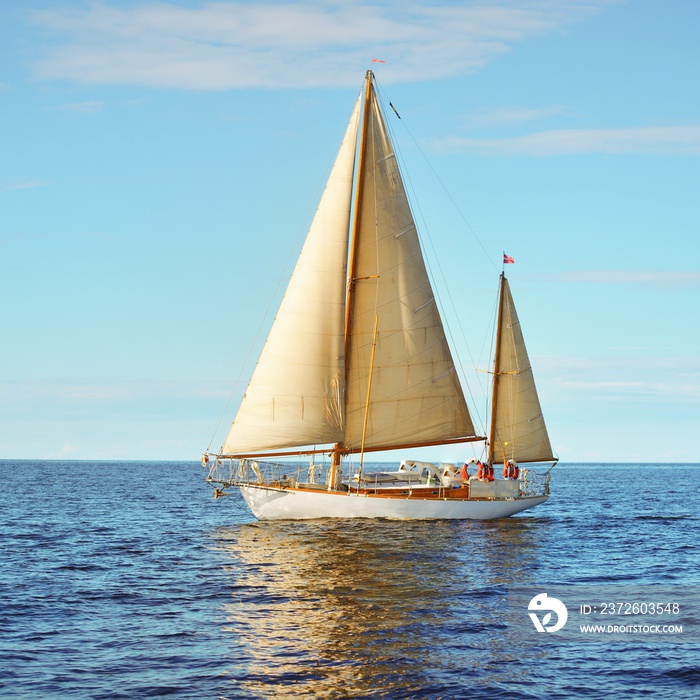 Vintage wooden two mast yacht sailing in a open sea on a clear day