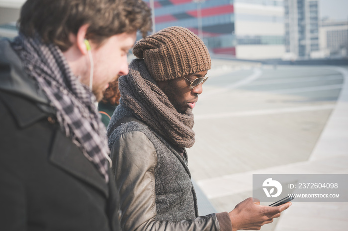 Two young men reading smartphone message on city street