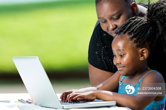 非洲母亲在笔记本电脑上帮助孩子。